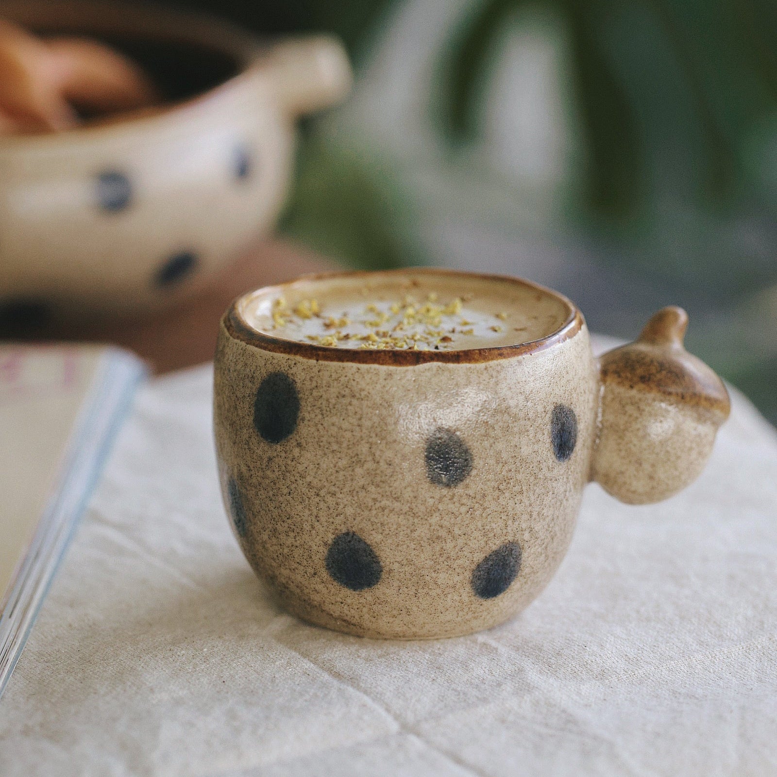 Ceramic mug with polka dot pattern on a light surface with a blurred green background