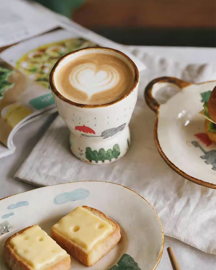 Cappuccino in a ceramic cup with a decorative lid, accompanied by a plate of bread on a table.