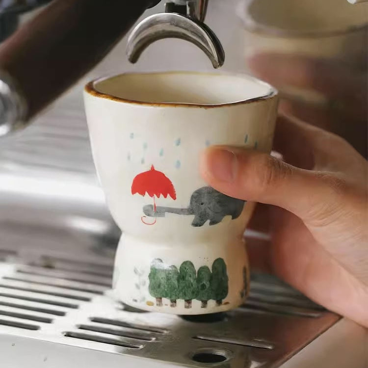 Espresso being poured into a small cup with cartoon designs.