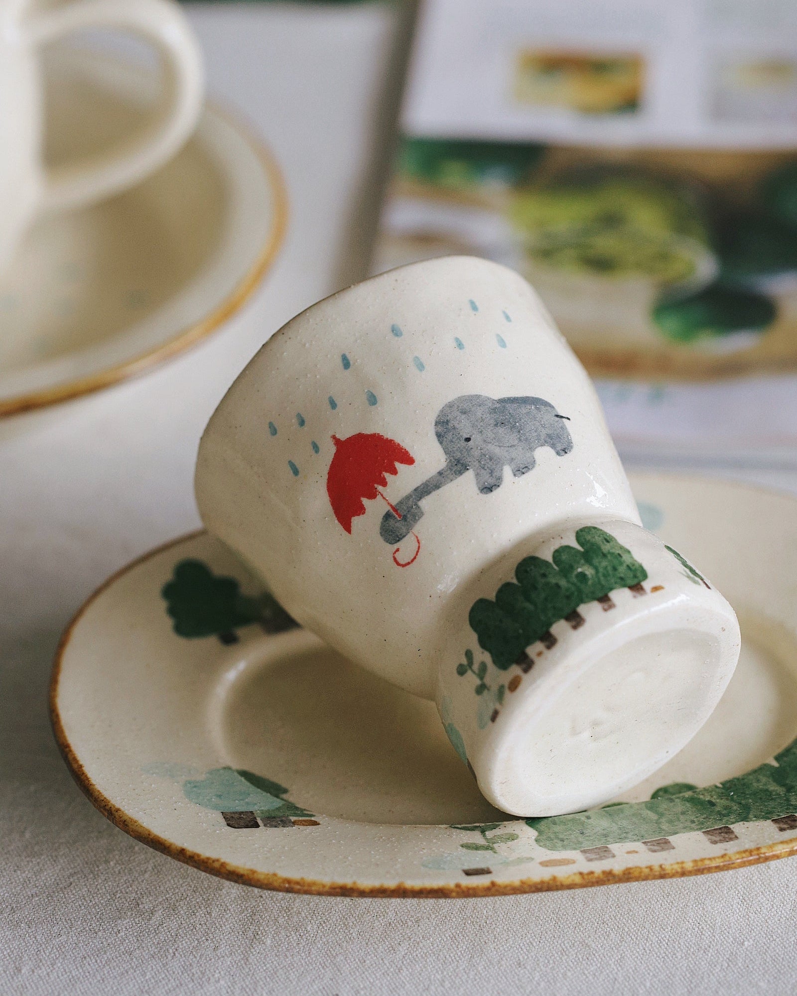 Ceramic cup with elephant design on a saucer, placed on a textured surface.