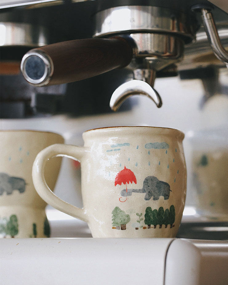 Espresso machine with a decorative mug featuring animal illustrations.