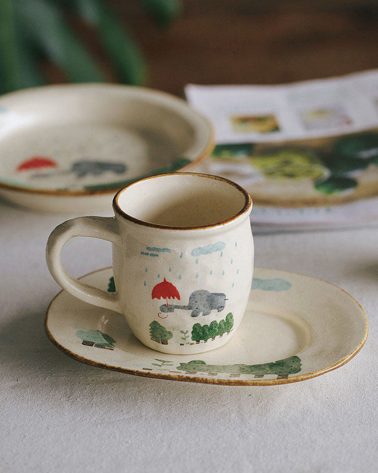 Ceramic cup and saucer with nature-themed design on a white surface.