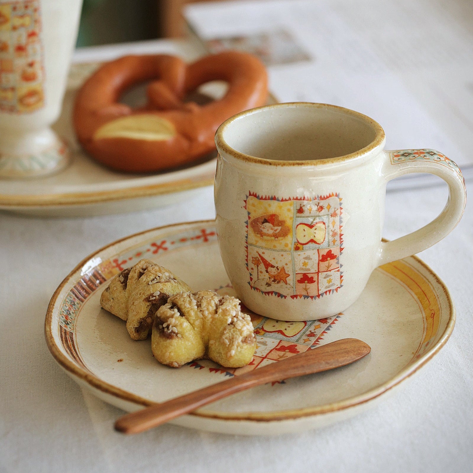 Cup of coffee with cookies and a pretzel on a plate, set on a table.