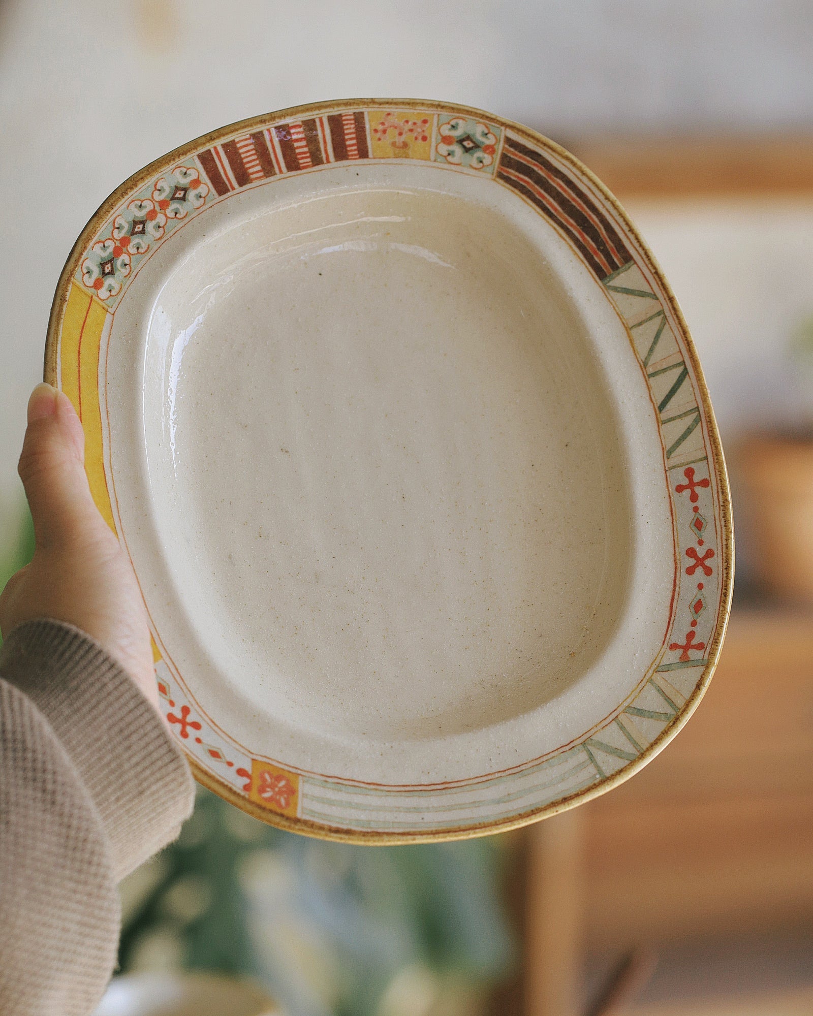 Decorative ceramic plate held by a hand with a blurred background