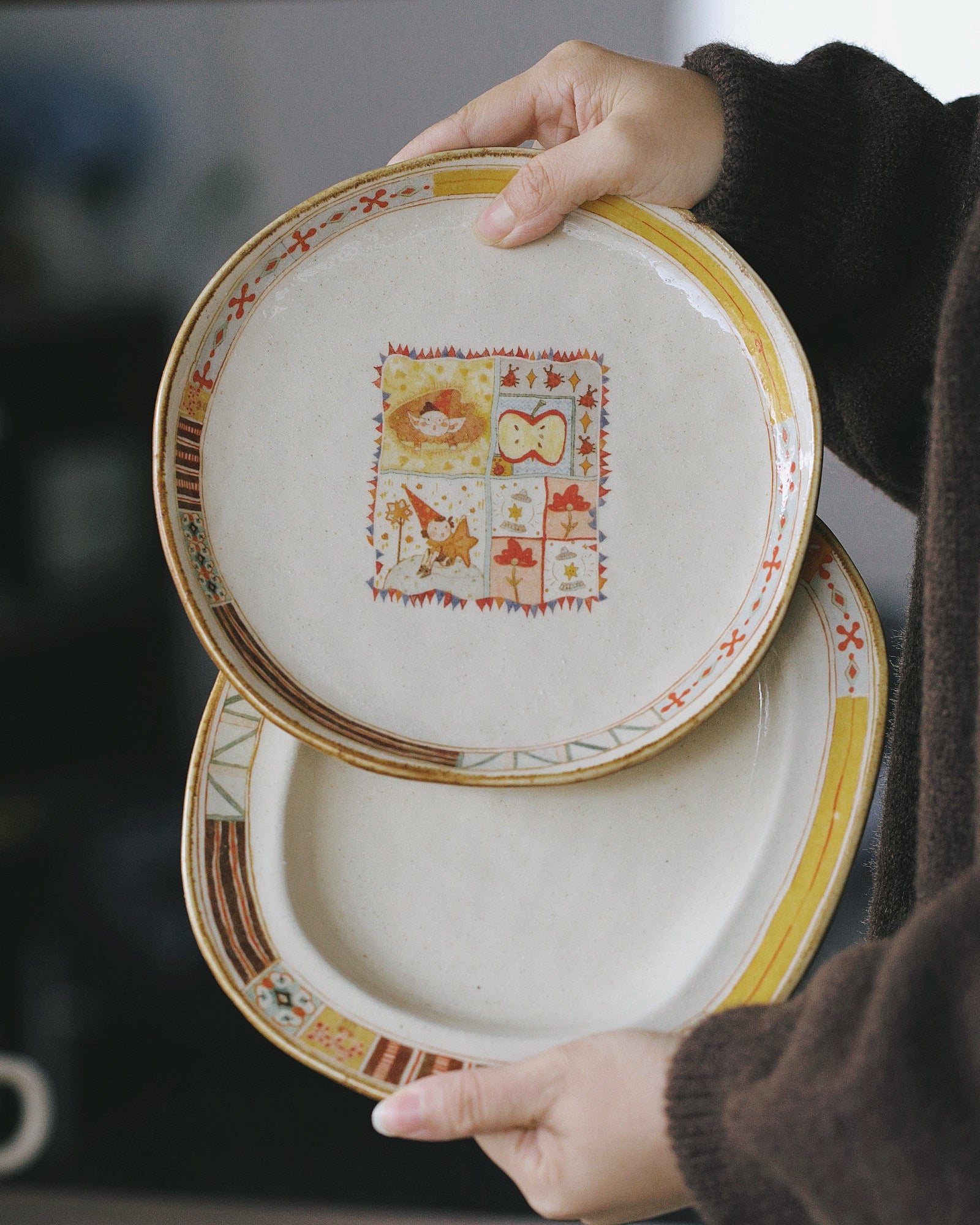 Two decorative plates held by a person against a blurred background
