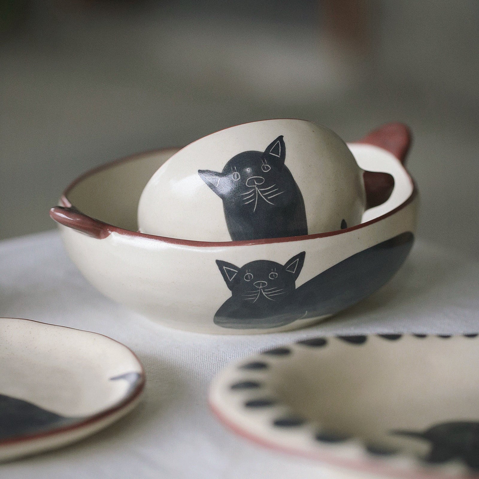 Ceramic bowls with cat designs on a light surface