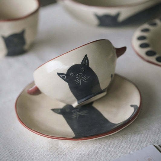 Ceramic cup and saucer with cat design on a light surface