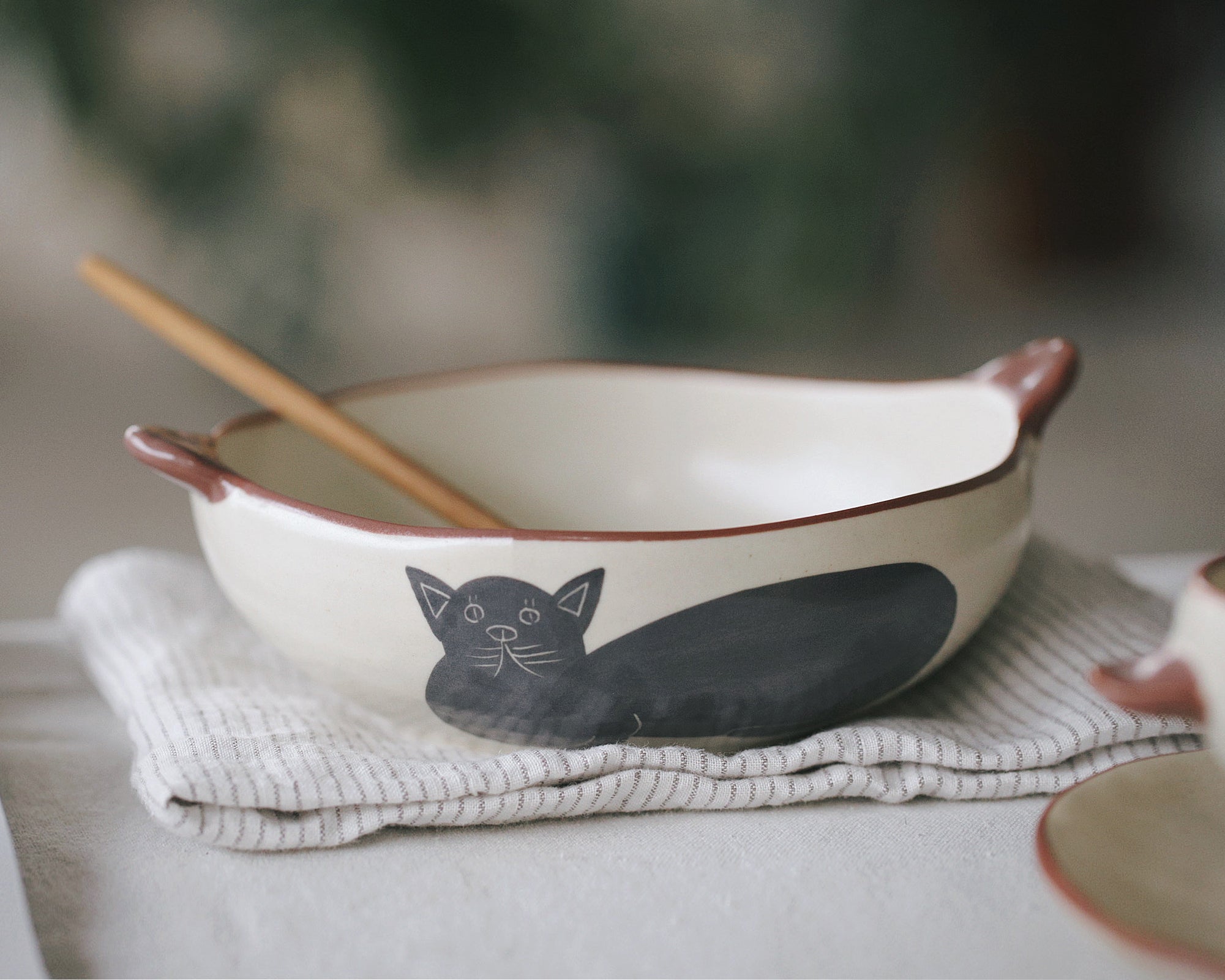 Ceramic bowl with cat design on a table with a blurred background