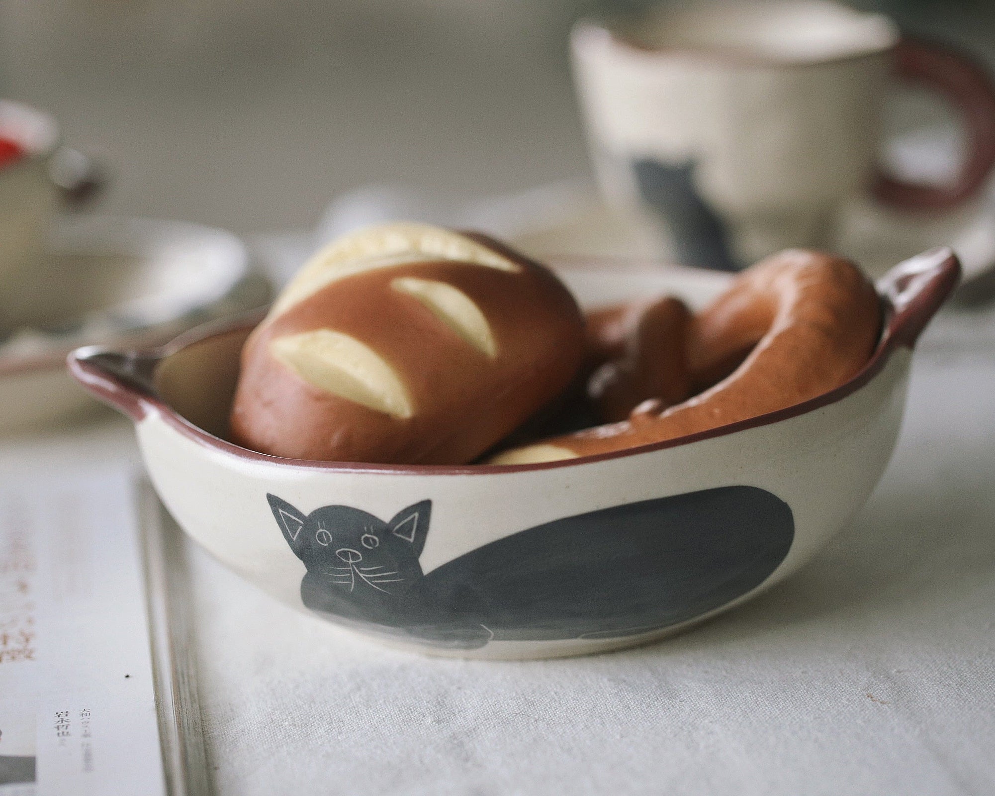 Ceramic bowl with cat design containing pastries on a table.