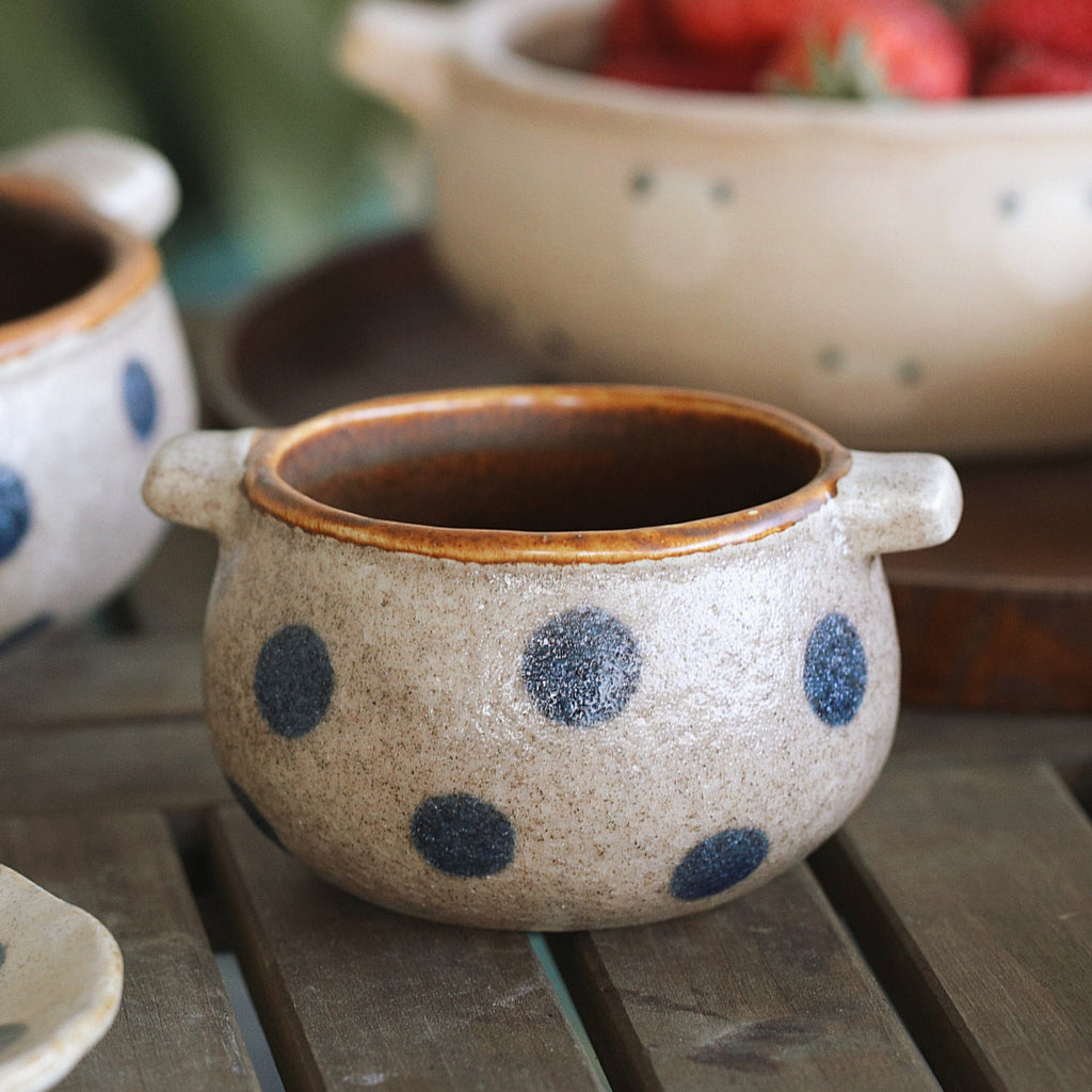 Ceramic pot with blue polka dots on a wooden surface