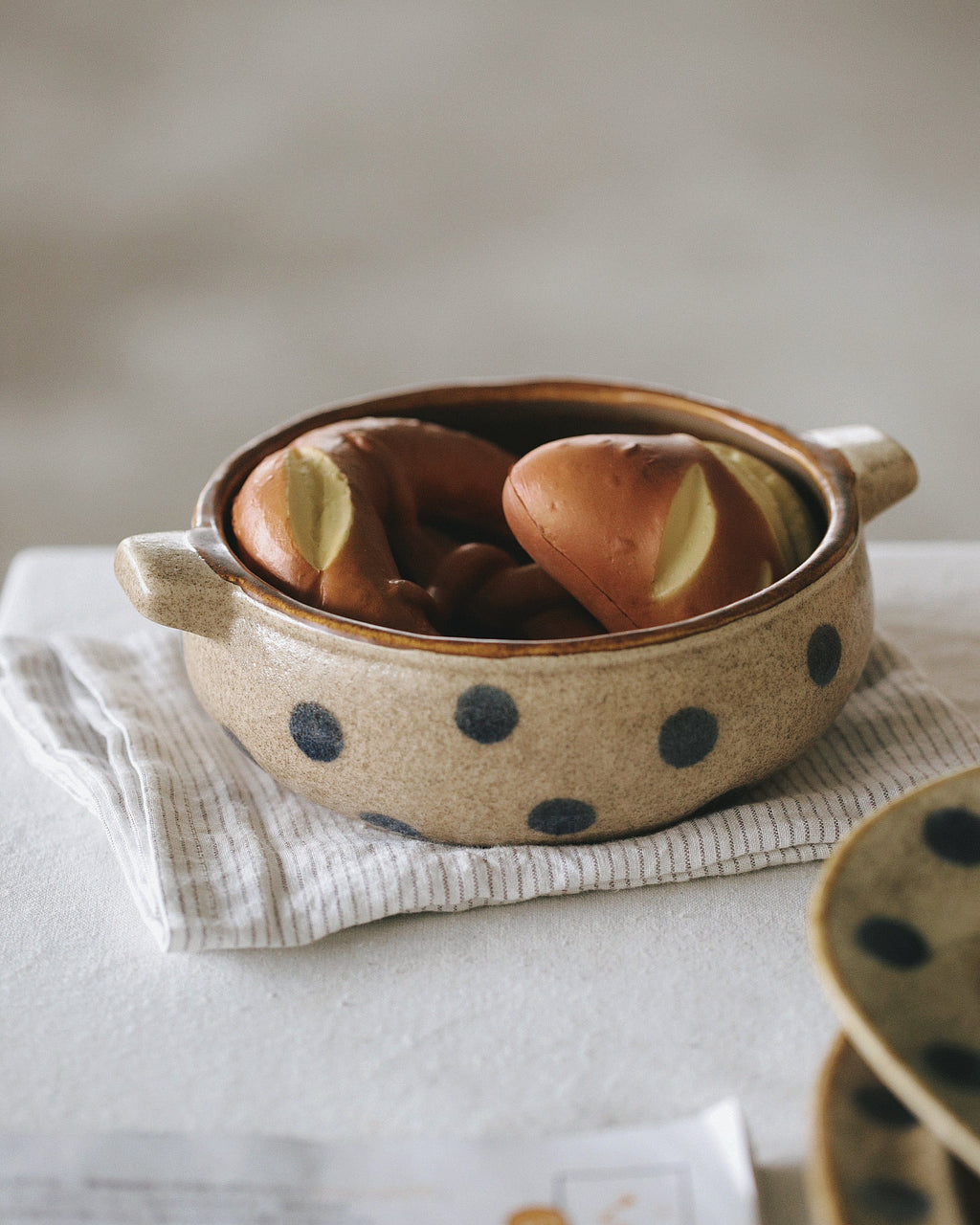 Ceramic bowl with polka dot pattern containing bread on a light surface.