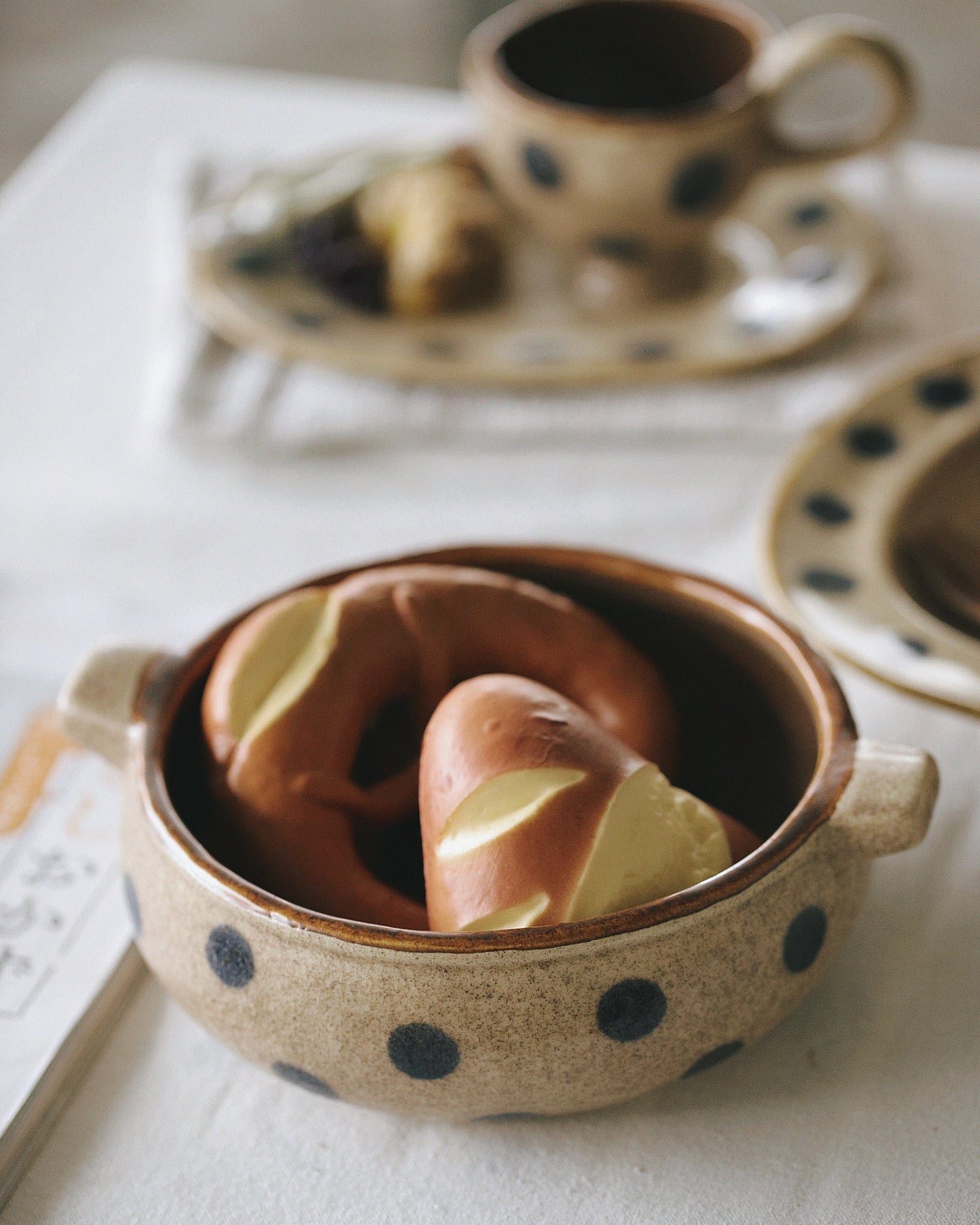 Ceramic bowl with polka dot pattern containing a heart-shaped cookie on a light background