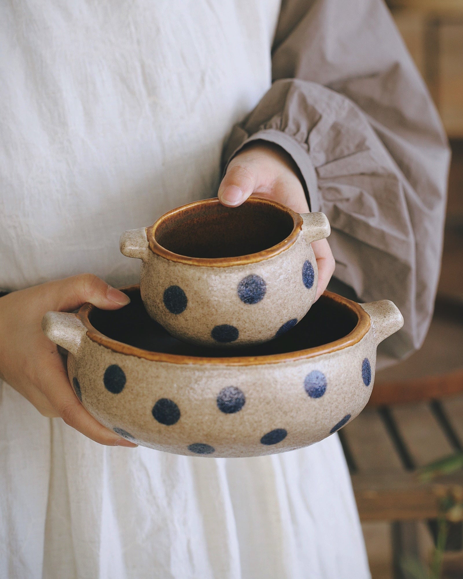 Person holding a ceramic bowl with blue polka dots