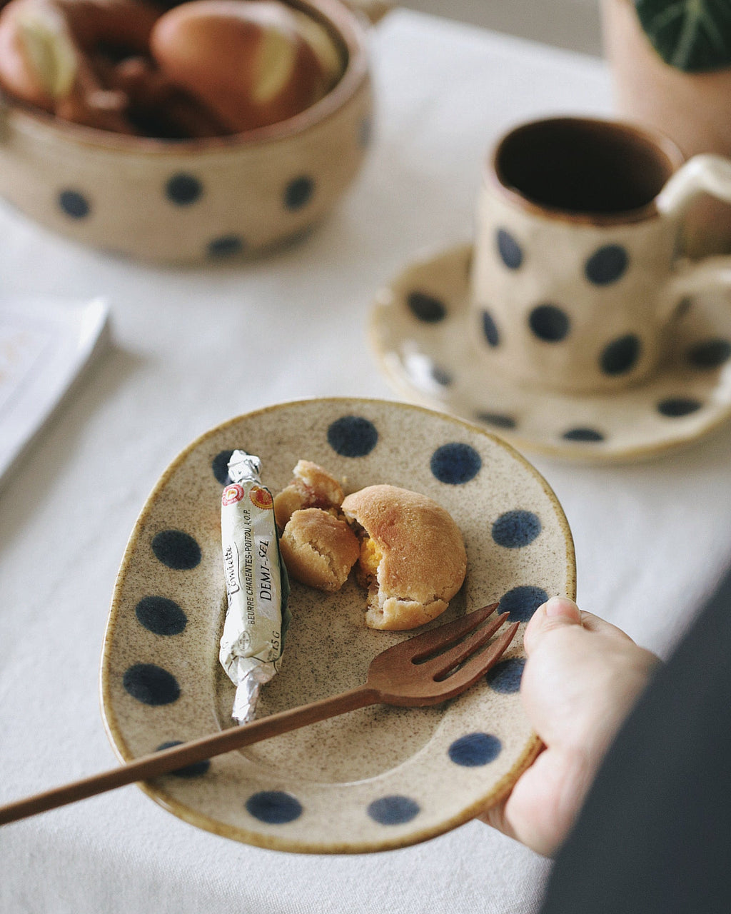 Polka dot ceramic plate with food and a cup of coffee on a light surface.