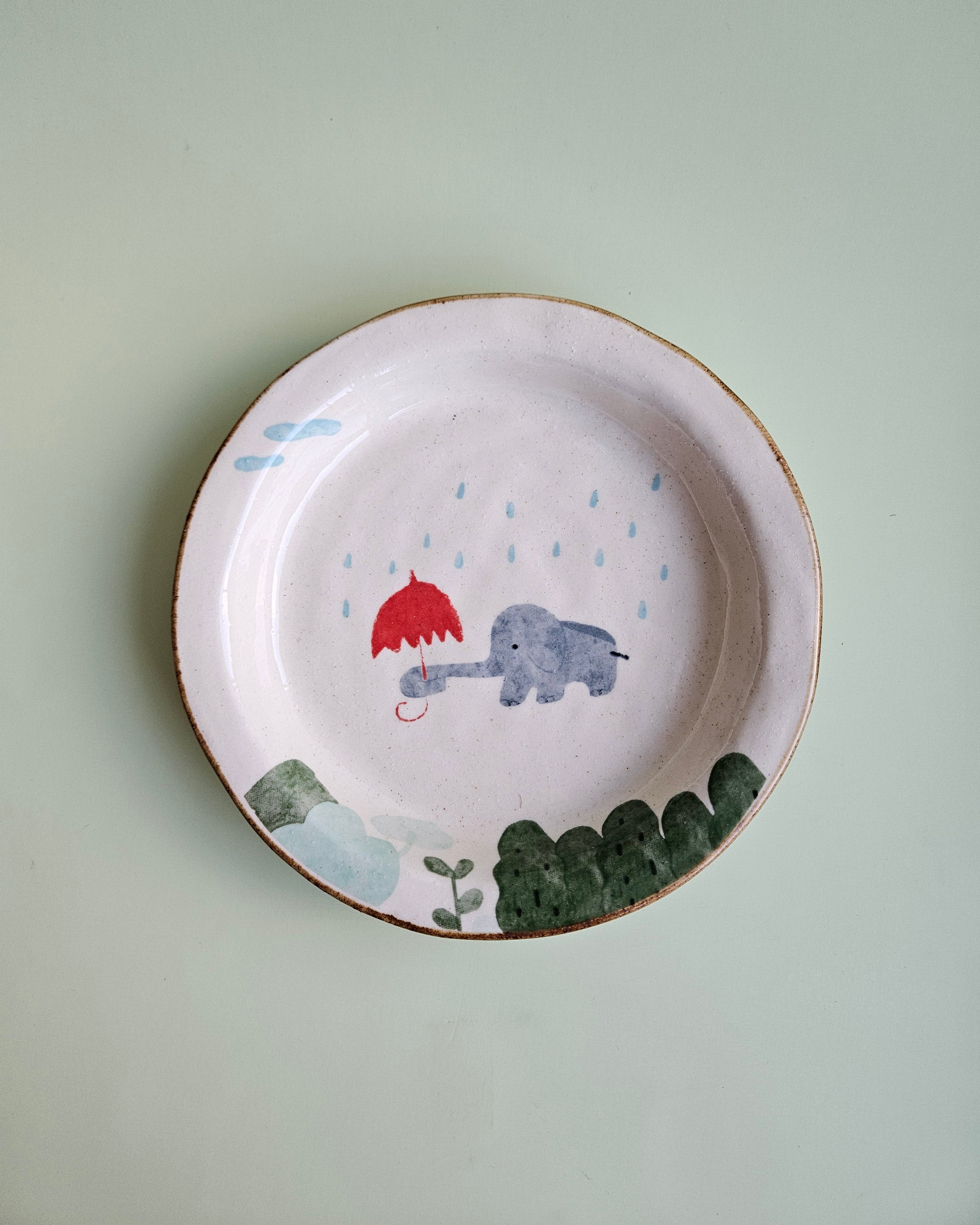 Ceramic plate with a cartoon design of a cat, fish, and leaf on a light green background