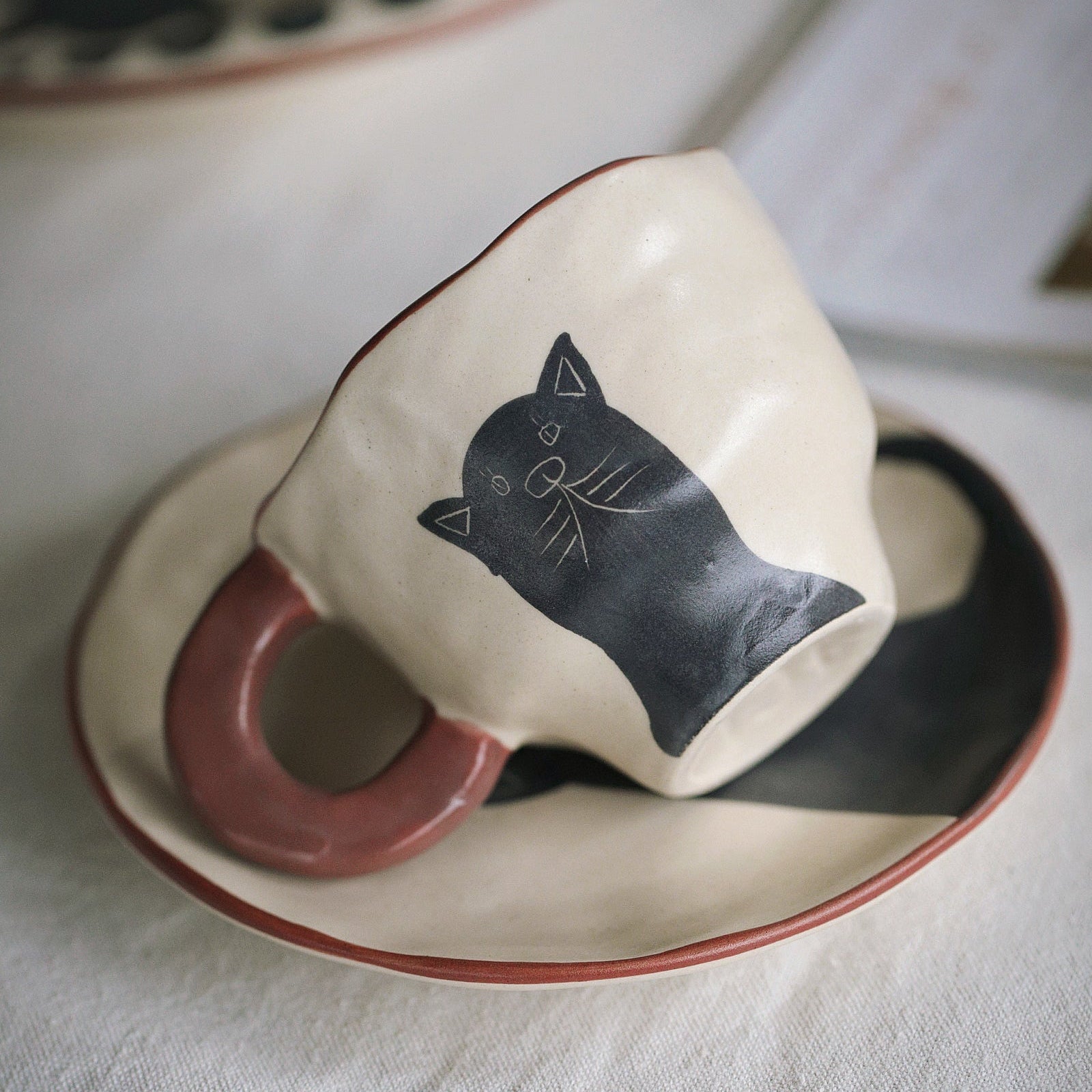 Ceramic cup and saucer with a black cat design on a white surface