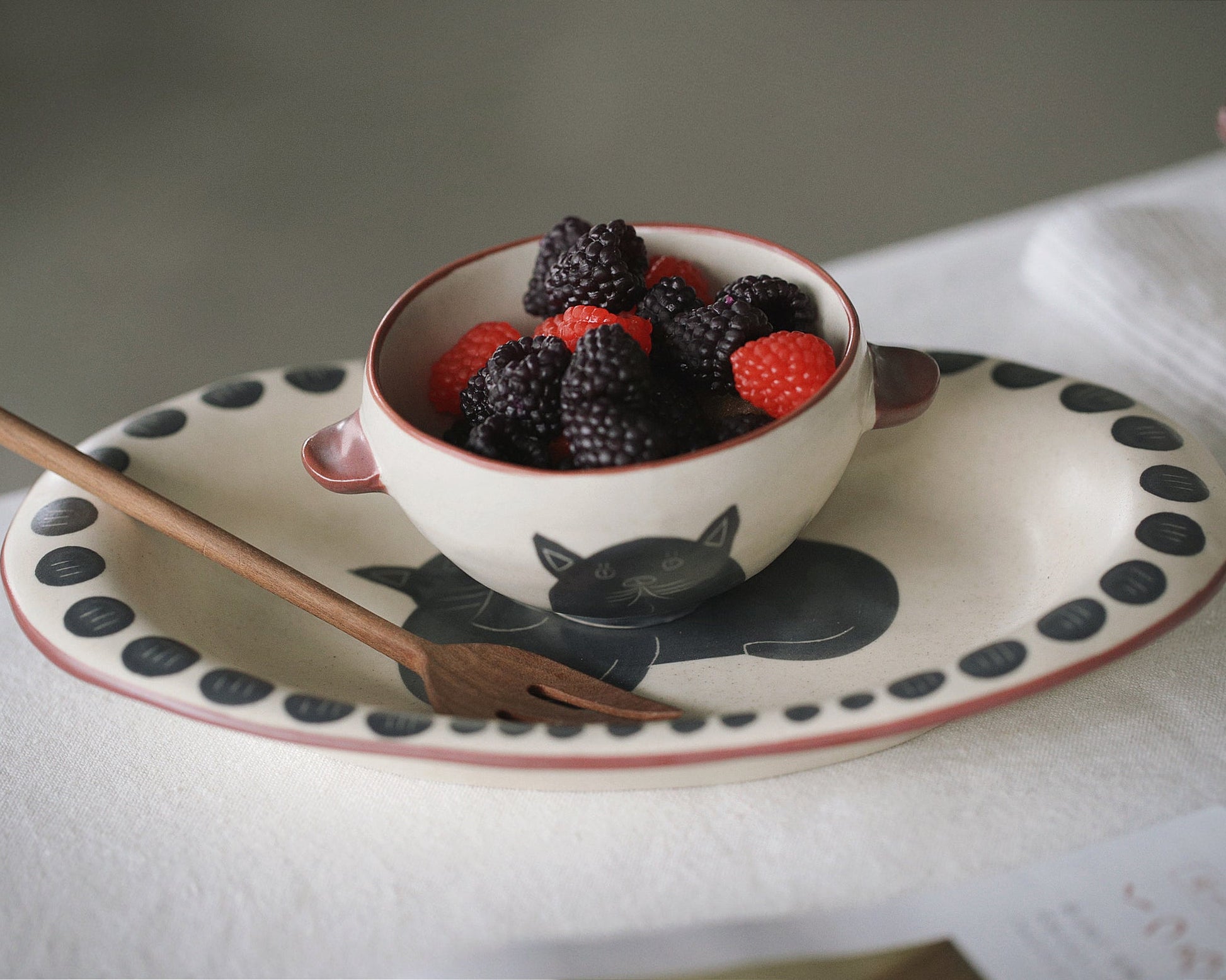 Bowl of berries on a decorative plate with a spoon