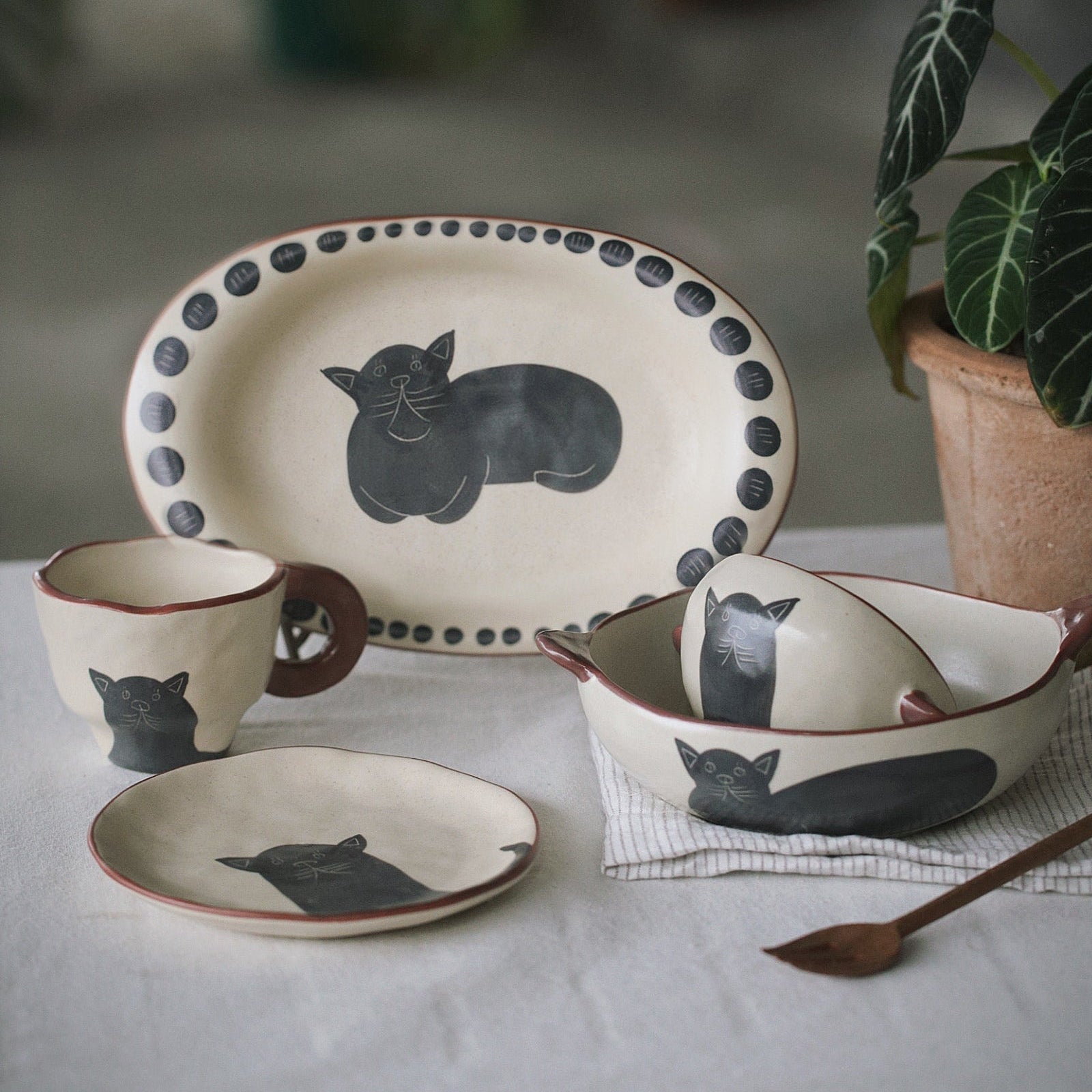 Ceramic tableware set with cat designs on a white surface.