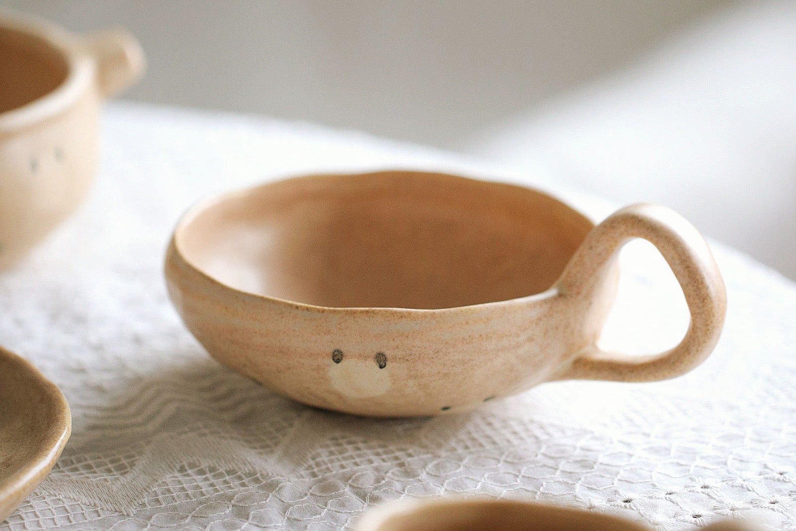 Ceramic bowl with a handle on a textured surface