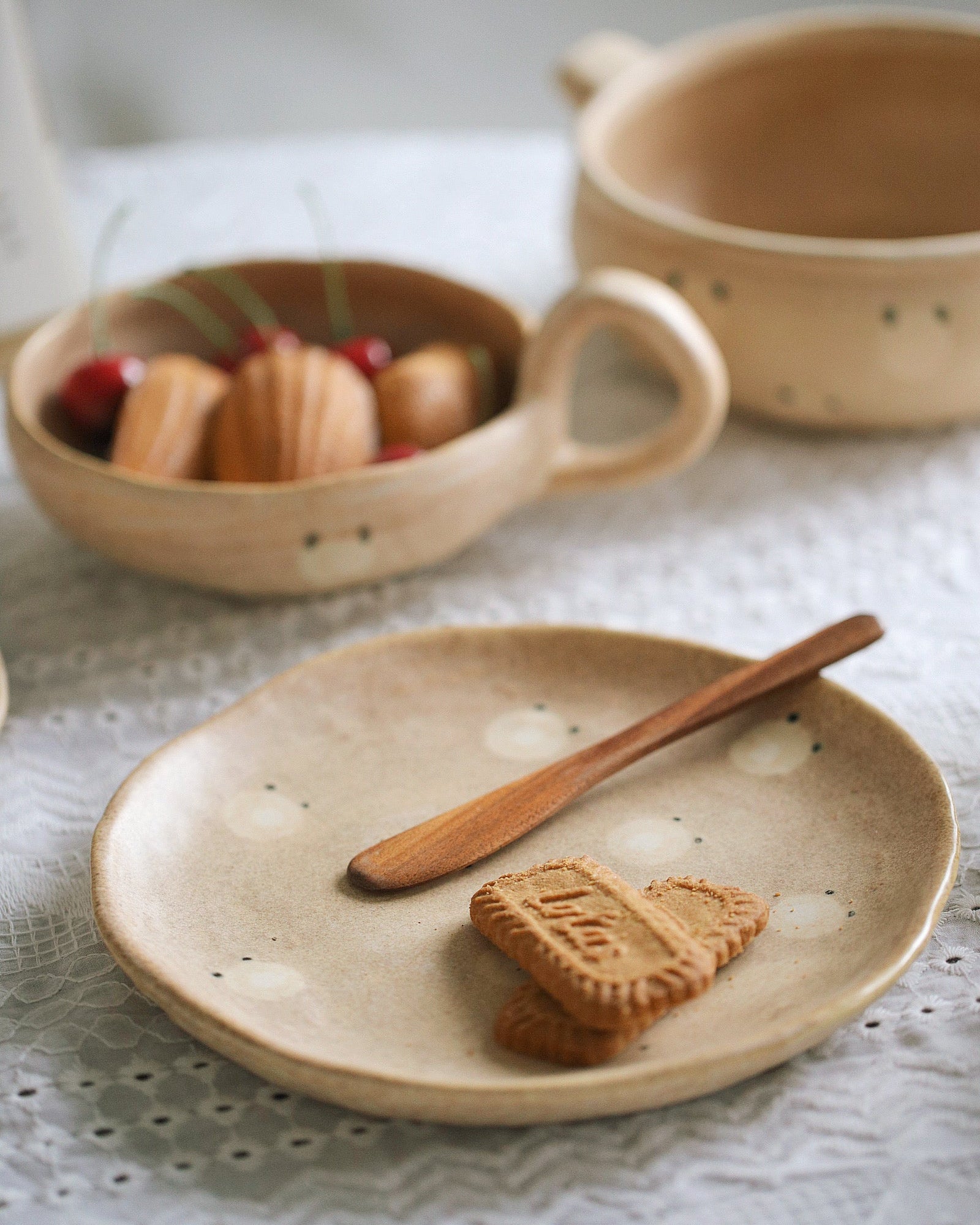 Ceramic plate with cookies and a wooden spoon on a textured surface