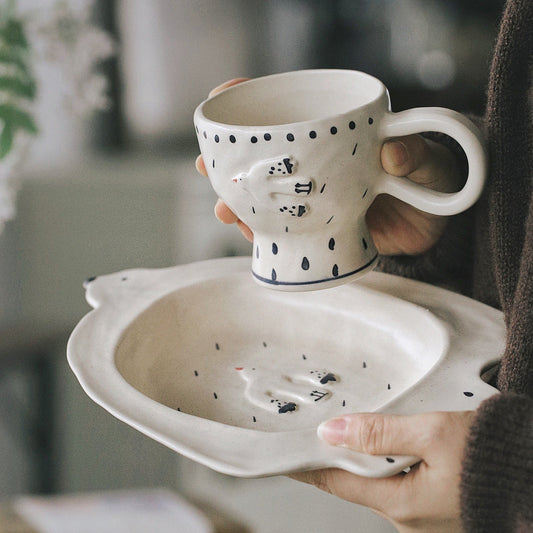 Person holding a ceramic cup with a decorative design on a blurred indoor background