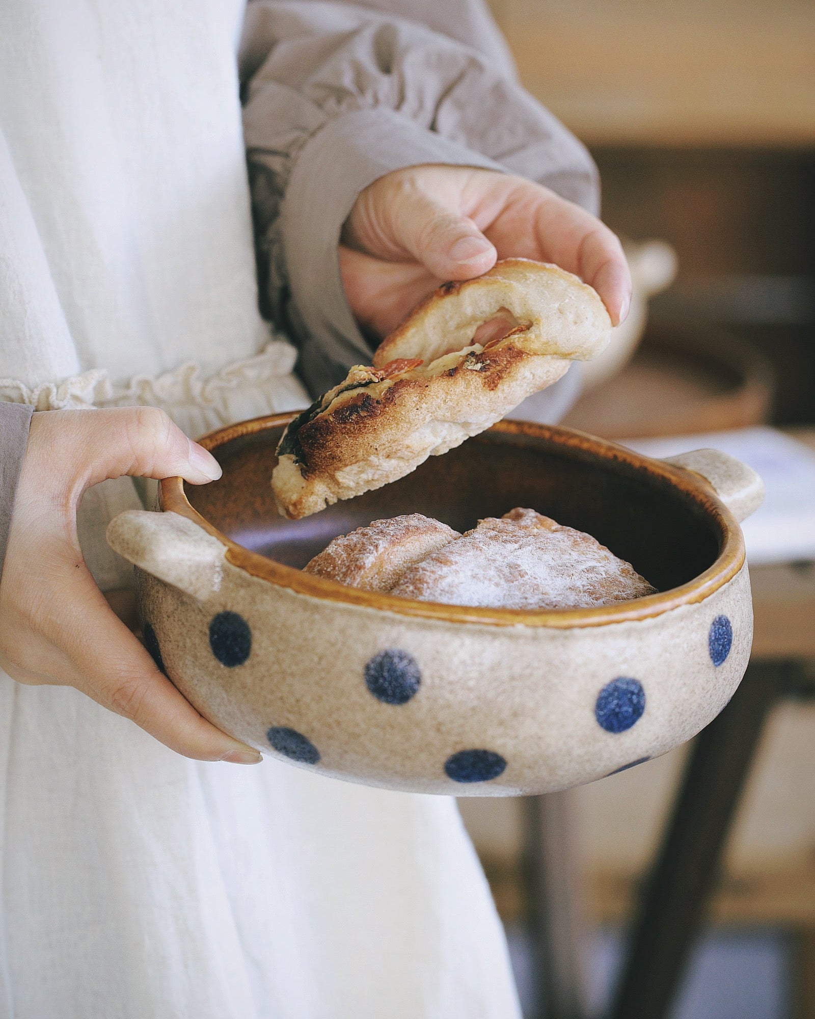 Person holding a polka dot bowl with bread and pastries