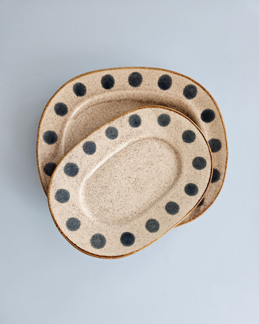 Set of two ceramic plates with black polka dots on a light gray background
