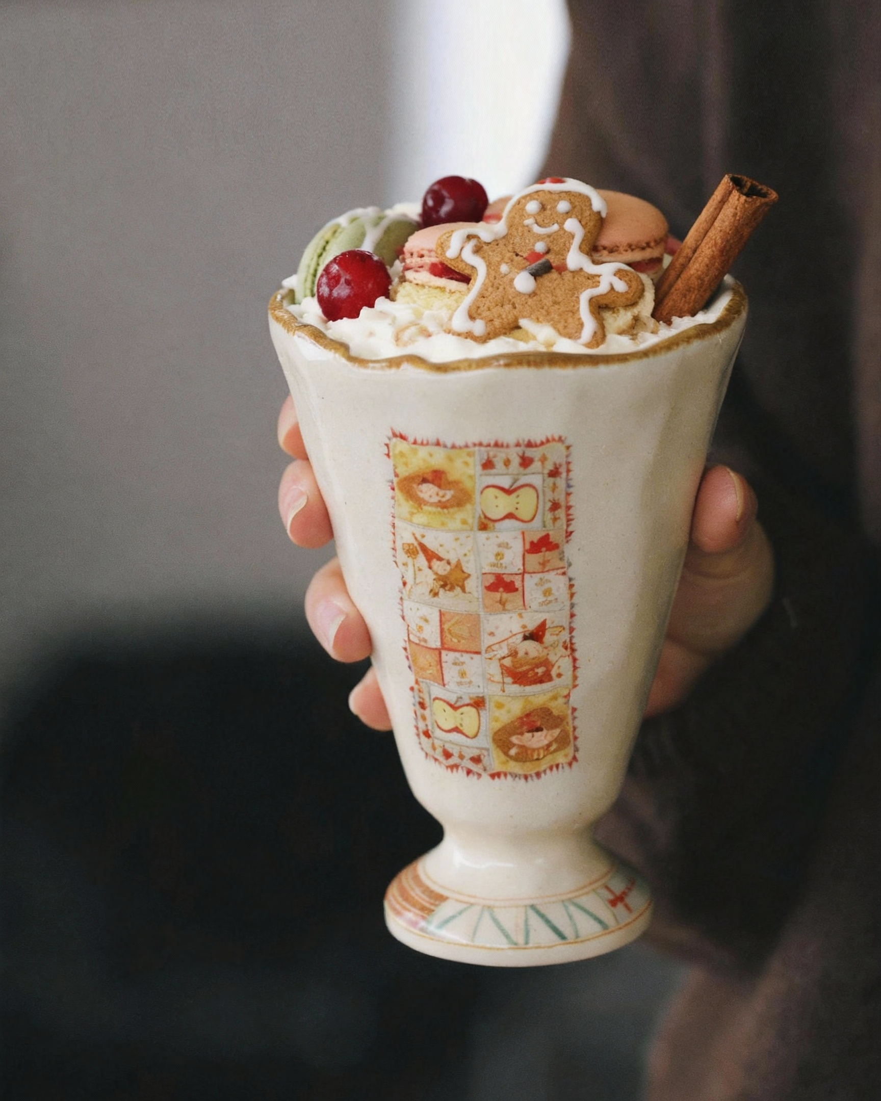 Decorative cup with hot chocolate and toppings held by a person