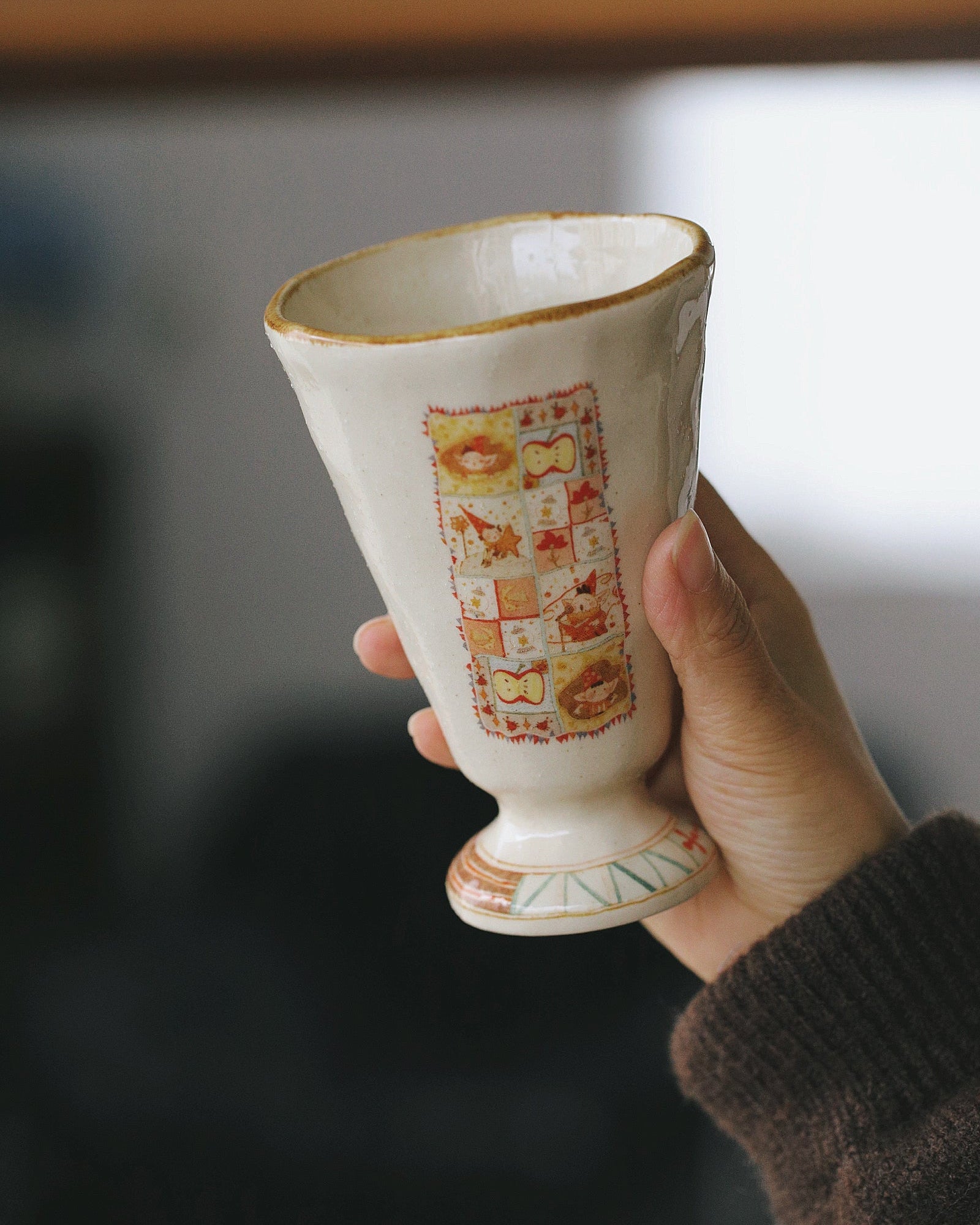Ceramic cup with decorative pattern held by a hand against a blurred background