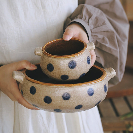 Person holding a ceramic bowl with blue polka dots