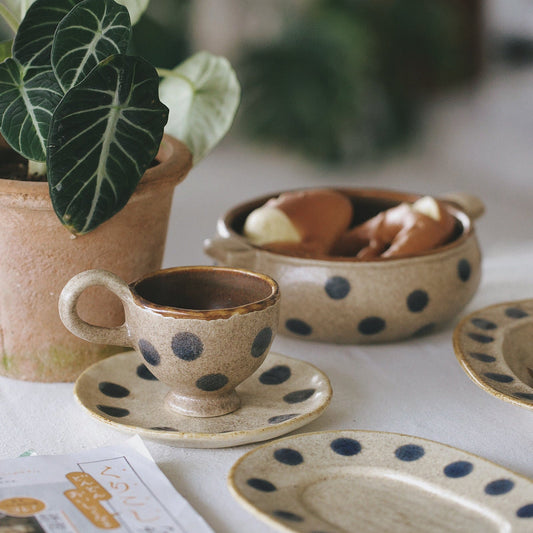 Ceramic dishes with polka dot patterns on a table with a plant in the background