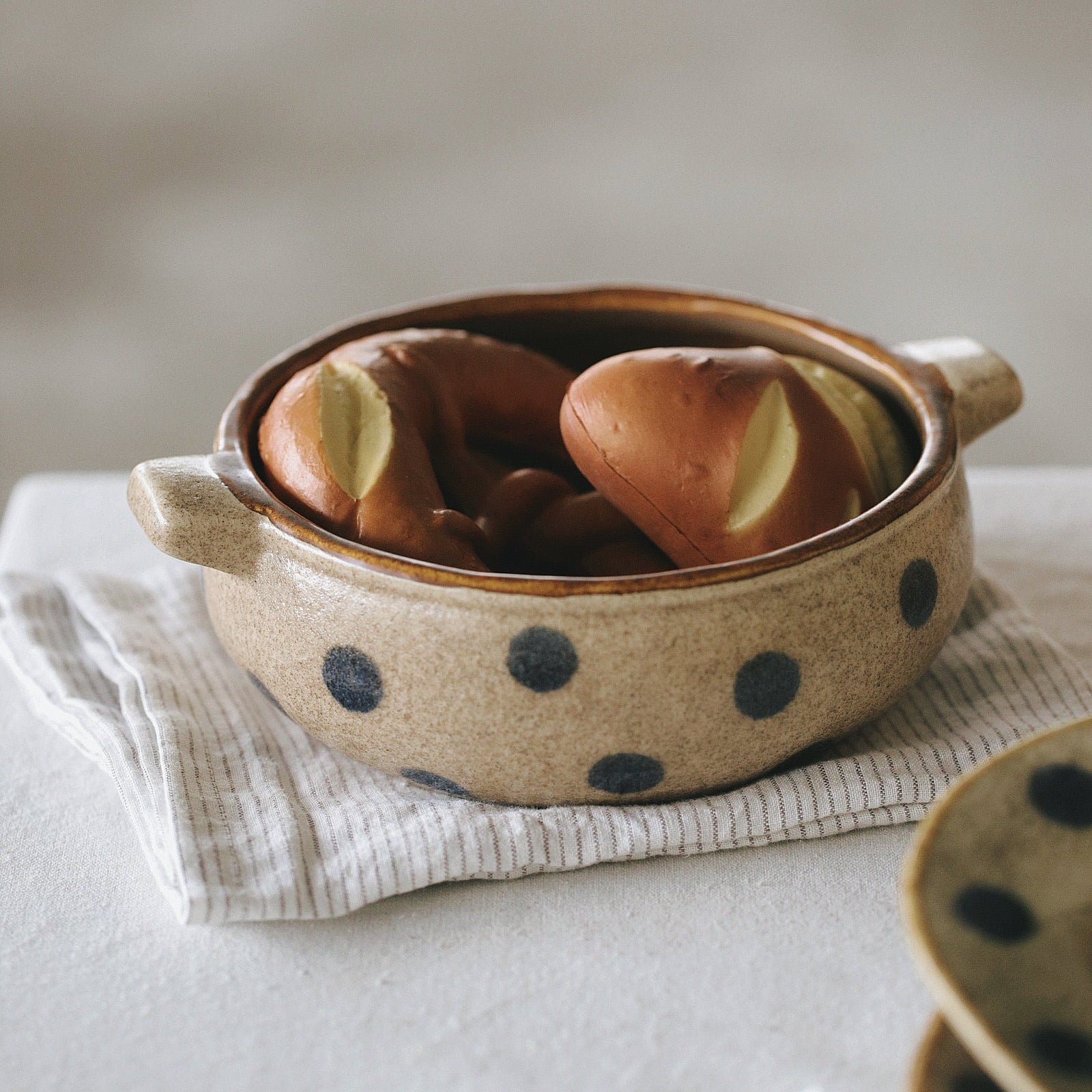 Ceramic bowl with polka dot pattern containing bread on a light surface.