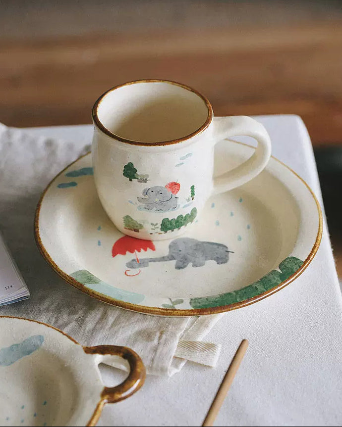 Ceramic cups and saucers with animal illustrations on a table.